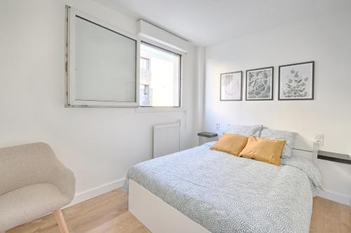 a white bedroom with a bed and a chair at Le Vitry - Appt 2 Chambres à 20min Orly in Vitry-sur-Seine