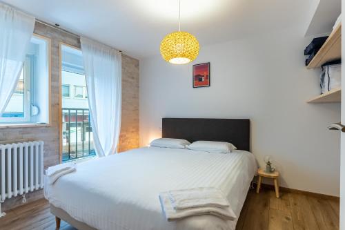 a bedroom with a large bed and a large window at Le 05-GregIMMO-Appart'Hôtel in Montbéliard