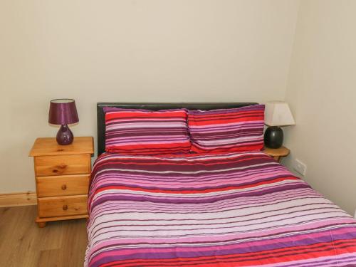 a bed with a striped blanket and a nightstand with a lamp at Glebe House in Ballinrobe