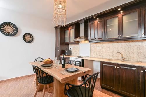 a kitchen with a wooden table and black cabinets at Delight Apartments suites in Stelida