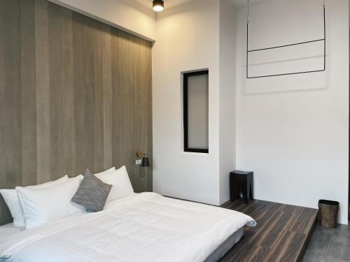 a bedroom with a white bed and a wall at 北濱渡日號民宿Dotoday Teahouse-自助入住 in Hualien City