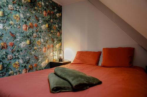 a bedroom with a red bed with a floral wallpaper at Ruim en landelijk appartement in Wolphaartsdijk