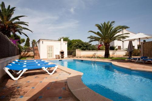 a swimming pool with a blue and white bench next to a house at Llampudol -Villa Sa Coma- in Sa Coma