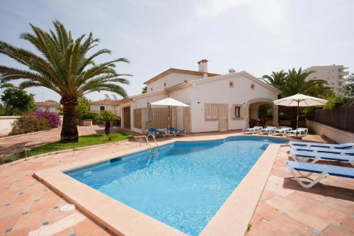 a swimming pool with chairs and a house at Llampudol -Villa Sa Coma- in Sa Coma