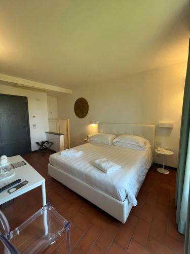 a bedroom with a large white bed and a table at Villa I Barronci Resort & Spa in San Casciano in Val di Pesa