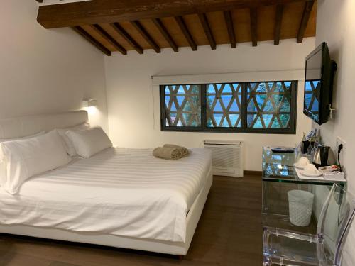 a bedroom with a white bed and a window at Villa I Barronci Resort & Spa in San Casciano in Val di Pesa
