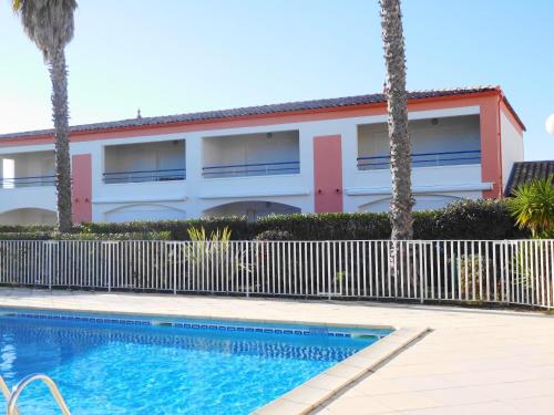 un bâtiment avec une piscine en face d'une maison dans l'établissement OREE DU GOLF II Joli T3 proche golf piscine Cap d Agde, au Cap d'Agde