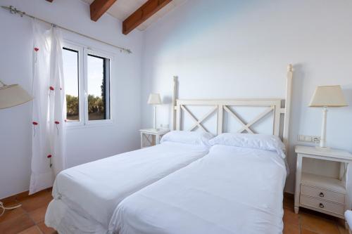 a white bedroom with a white bed and a window at Villas Finesse By MENORCARENTALS in Son Bou