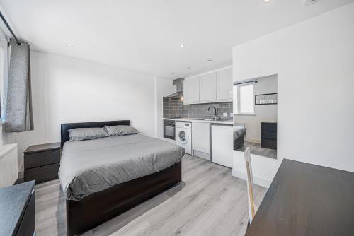 um quarto branco com uma cama e uma cozinha em Studio Flat in Camberwell em Londres