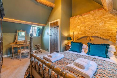 a bedroom with a large bed with blue pillows at Broughwood Cottage Snowshill in Broadway