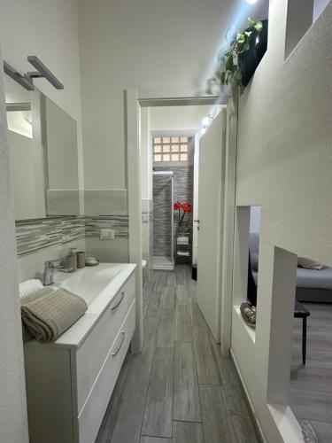 La salle de bains blanche est pourvue d'un lavabo et d'un miroir. dans l'établissement Fior&Iris Apartments, à Stresa
