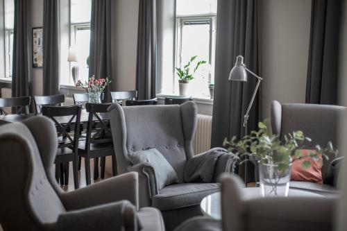 a living room with chairs and a table and windows at Vandrarhemmet Vindarnas Hus in Örnsköldsvik