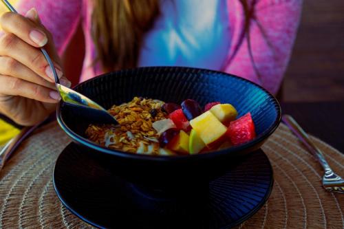 a person eating a bowl of cereal and fruit at TimBila Safari Lodge in Omaruru