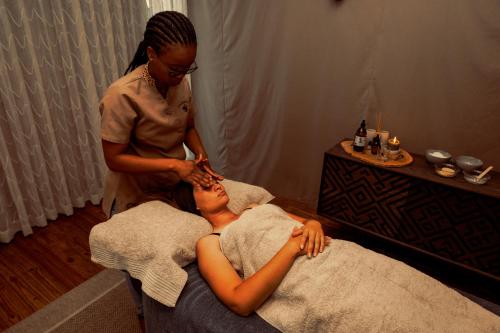 a woman getting her hair cut by a woman in a salon at TimBila Safari Lodge in Omaruru