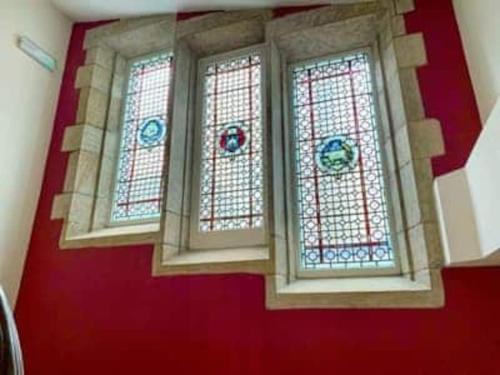 drei Buntglasfenster in einem Raum mit roten Wänden in der Unterkunft The Old Ship Hotel, apartment 2 in Skipton