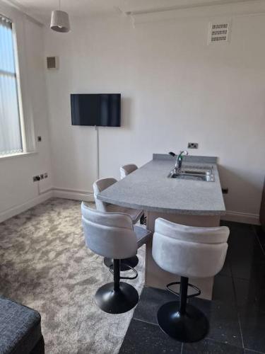 a kitchen with a counter with chairs and a sink at The Old Ship Hotel, apartment 2 in Skipton