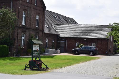 un panneau devant un bâtiment en briques avec une voiture dans l'établissement Gästezimmer „Hühnerwiese“, à Xanten