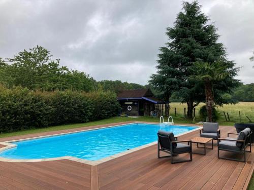 einen Pool mit Stühlen und eine Holzterrasse in der Unterkunft Cottage proche circuit 24 Heures Le Mans proche de Paris Jeux olympiques autoroute à 5km in La Chapelle-Saint-Rémy