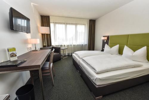 a hotel room with a bed and a desk at Hotel Vorfelder in Walldorf