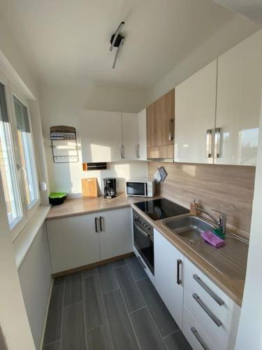una pequeña cocina con armarios blancos y fregadero en City Apartment Tulln, en Tulln