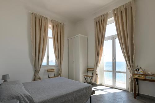 a bedroom with a bed and large windows at Hotel Miramare in Spotorno