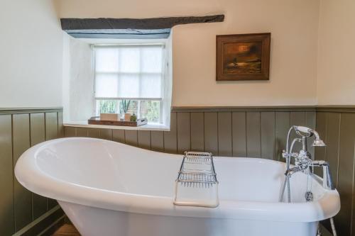 a white tub in a bathroom with a window at Castle Cottage Winchcombe in Winchcombe