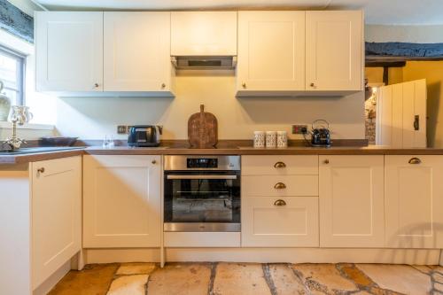 cocina con armarios blancos y horno en Stunning 2 Bed Cotswold Cottage Winchcombe, en Winchcombe