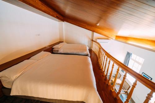 two beds in a small room with a staircase at 中央旅社 in Magong