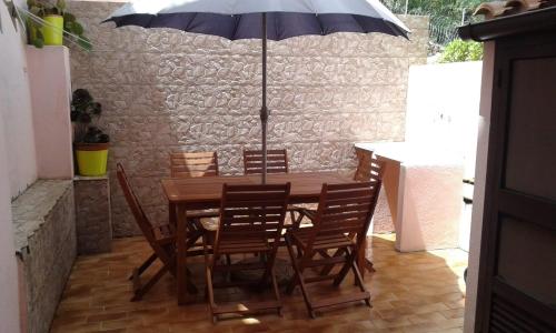 a wooden table with chairs and an umbrella at Villetta a schiera in La Maddalena