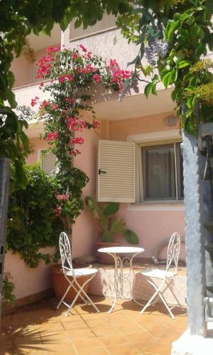 a table and chairs in front of a building with flowers at Villetta a schiera in La Maddalena