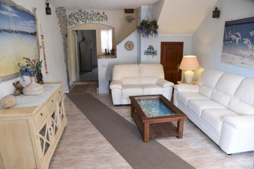 uma sala de estar com dois sofás brancos e uma mesa de centro em Villetta a schiera em La Maddalena