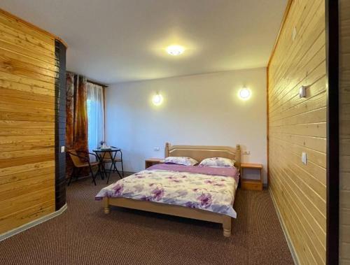 sypialnia z łóżkiem i drewnianą ścianą w obiekcie CASA DE VACANTA CLARA MARIA w mieście Comarnic