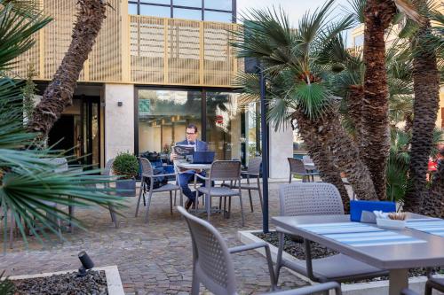 a man sitting at a table in a restaurant with a laptop at Fly Decó Hotel in Lido di Ostia
