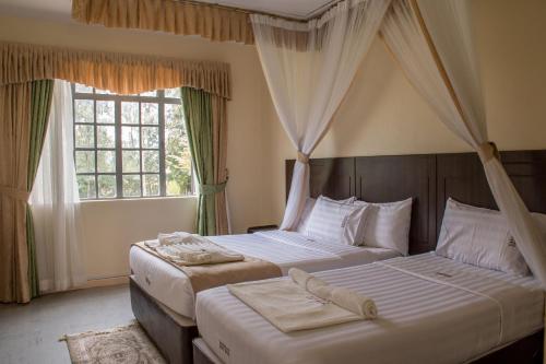 2 Betten in einem Schlafzimmer mit 2 Fenstern in der Unterkunft Lake Bogoria Spa Kabarak in Nakuru