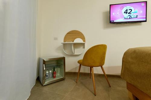 Habitación con silla y TV en la pared. en La casa di Chele en Palermo