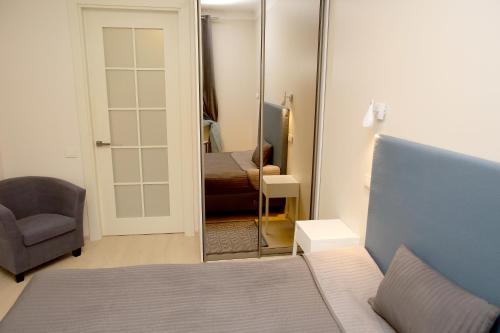 1 dormitorio con espejo, 1 cama y 1 silla en Cathedral Apartments, en Vilna