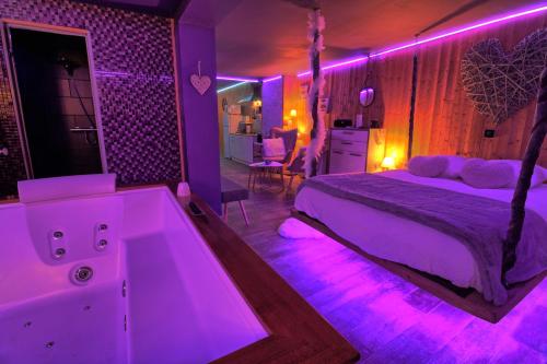 - une chambre avec un lit et une baignoire avec des lumières violettes dans l'établissement Aux 67 nuances - Spa, à Châtenois