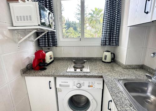 eine kleine Küche mit einer Waschmaschine und einem Waschbecken in der Unterkunft Skol 131 - Studio at Skol Building in Marbella centre with sea views. in Marbella