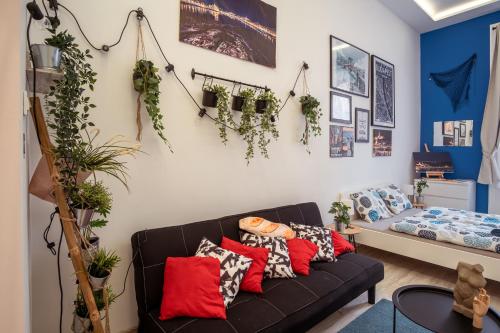 een woonkamer met een zwarte bank en planten aan de muur bij Király88 Apartment in Boedapest