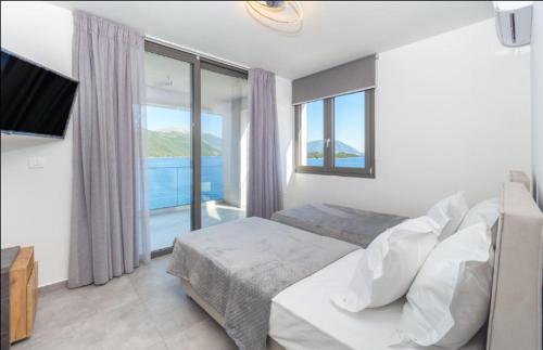 Mrs Grey Luxury Villa في ميغانيسي: غرفة نوم مع سرير وإطلالة على المحيط