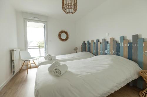 Un dormitorio blanco con 2 camas y una silla en Riviera - T3 avec piscine partagée et parking proche plage Arzon, en Arzon