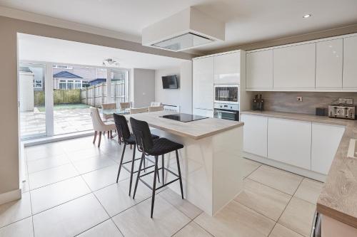 a kitchen with white cabinets and a island with bar stools at Host & Stay - Aidan Gardens in Durham