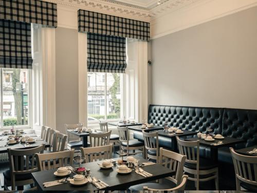 a dining room with tables and chairs and windows at Argyll Western Hotel in Glasgow