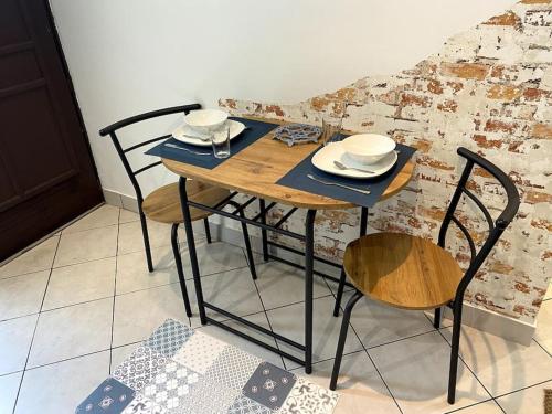 una mesa de madera con sillas y platos. en studio le 17 près de Paris, en Montlhéry