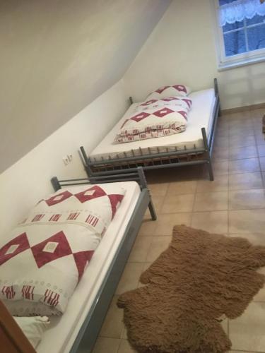 two twin beds in a room with a rug at Mecseki Farkasvár in Magyarhertelend