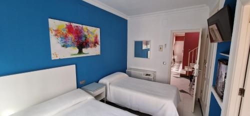 レペにあるPension el Patioのベッド2台が備わる客室で、壁には絵画が飾られています。
