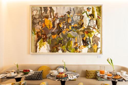 a painting hanging on a wall above two tables at Nerva Boutique Hotel in Rome