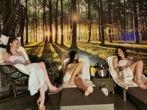 a group of three women sitting in chairs in a forest at Apartmány Fatrapark 1 s WELLNESSOM Hrabovská dolina in Ružomberok