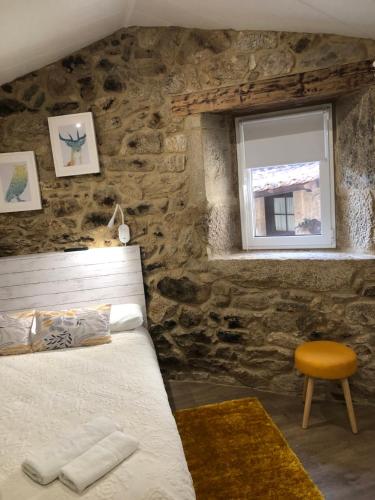 a bedroom with a bed and a window and a stool at Casa Arrabal in Oia