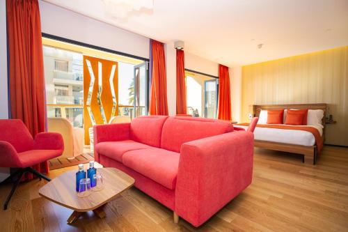 a living room with a red couch and a bed at Bohemia Suites & Spa - Adults Only in Playa del Ingles